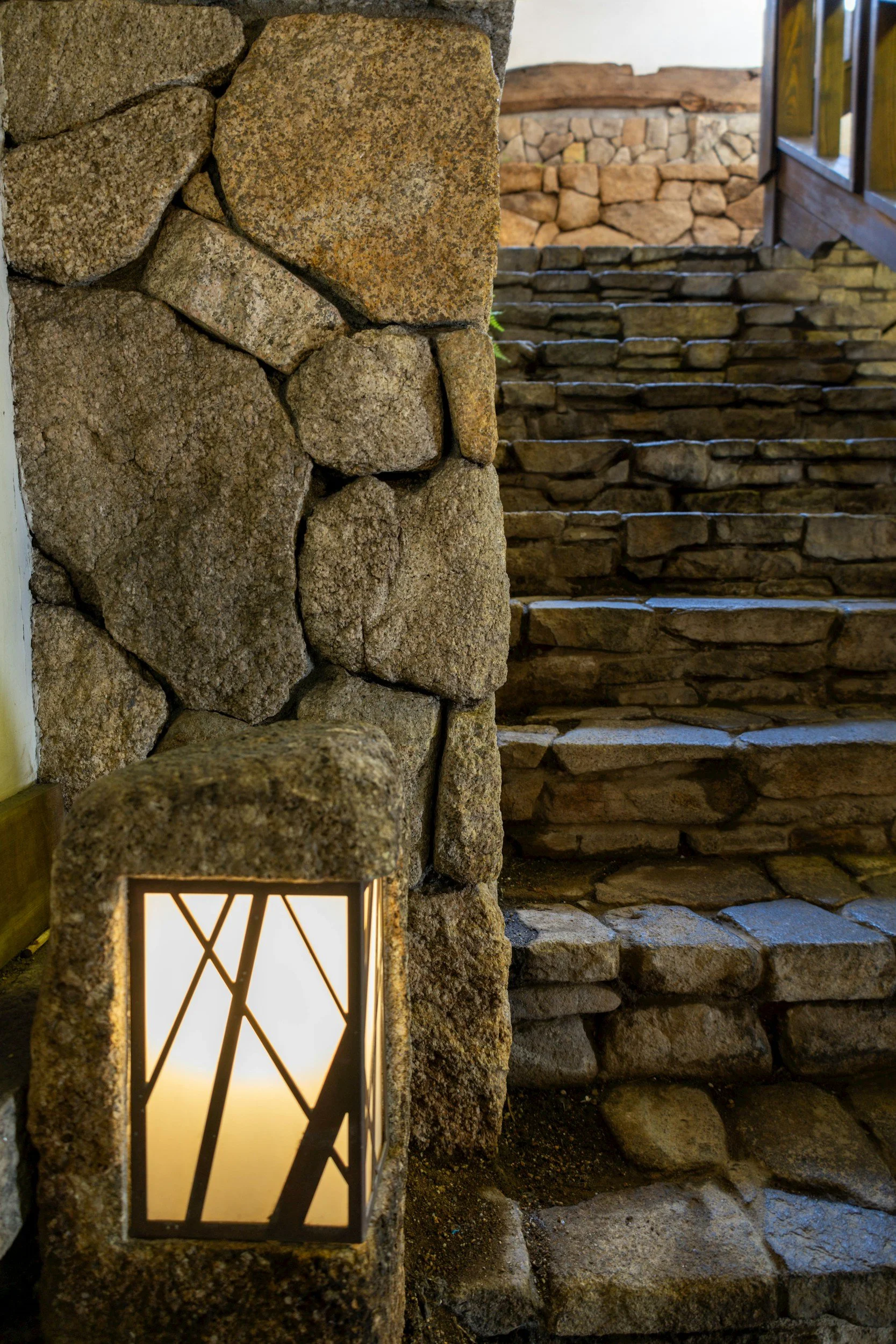 Steinige Außentreppe mit einer beleuchteten Laterne am Anfang.