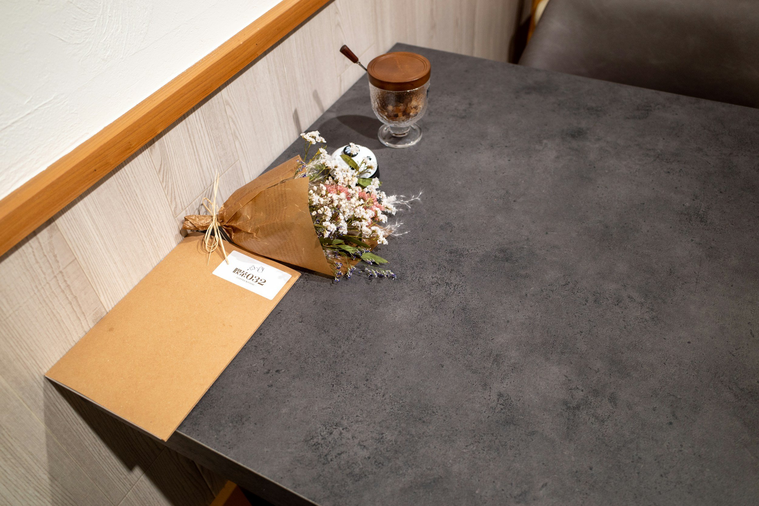 Ein Tisch mit einer Blumenstrauß, einer braunen Karte und einem Glas mit Keksen im Hintergrund.