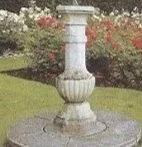 Ein dekorativer Brunnen im Garten mit Wasser und umliegender Blumenpracht.