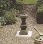 Steinerne Zauberspiegel im Garten, umgeben von Pflanzen.