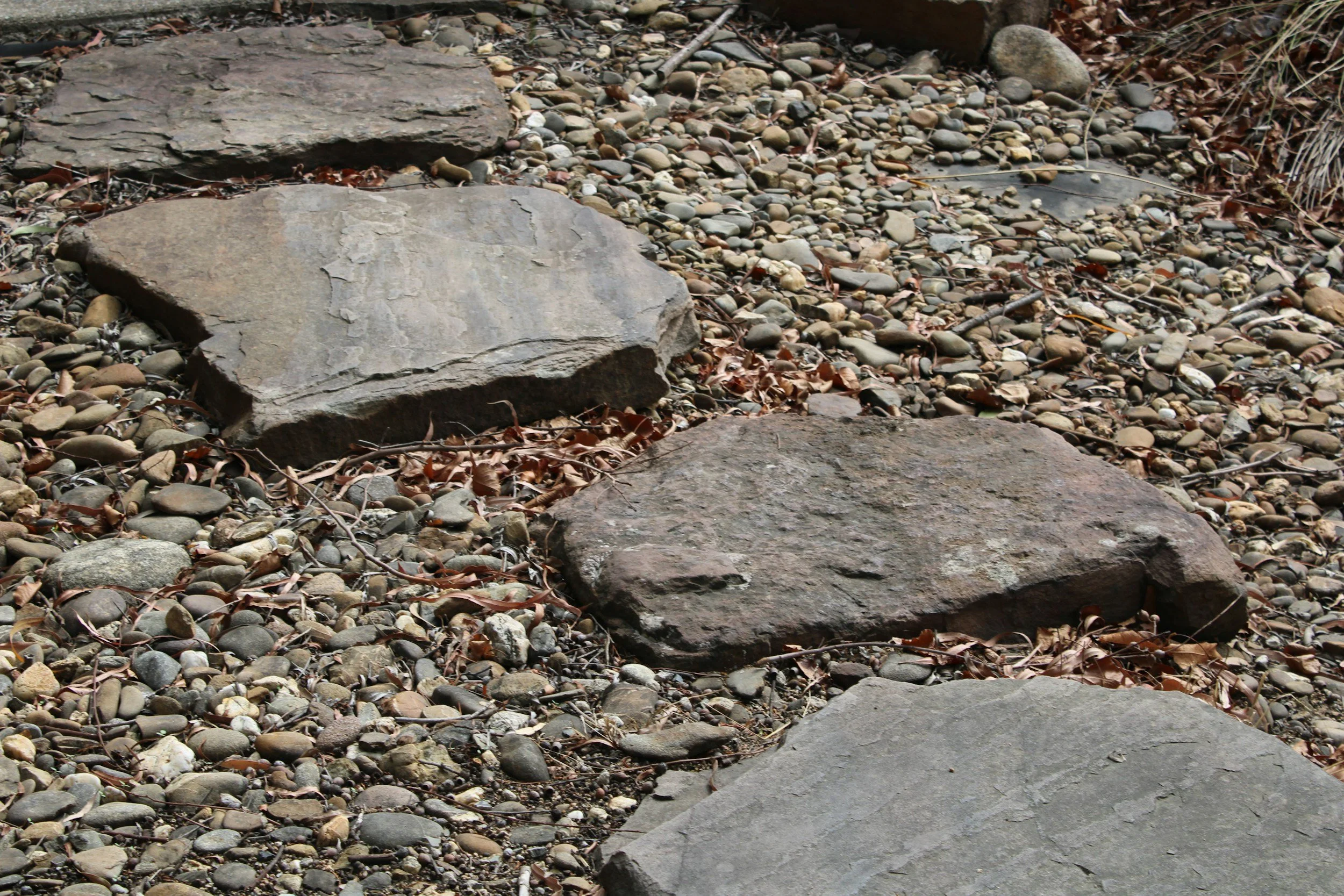 Mehrere große Steine und viele kleine Kiesel auf dem Boden