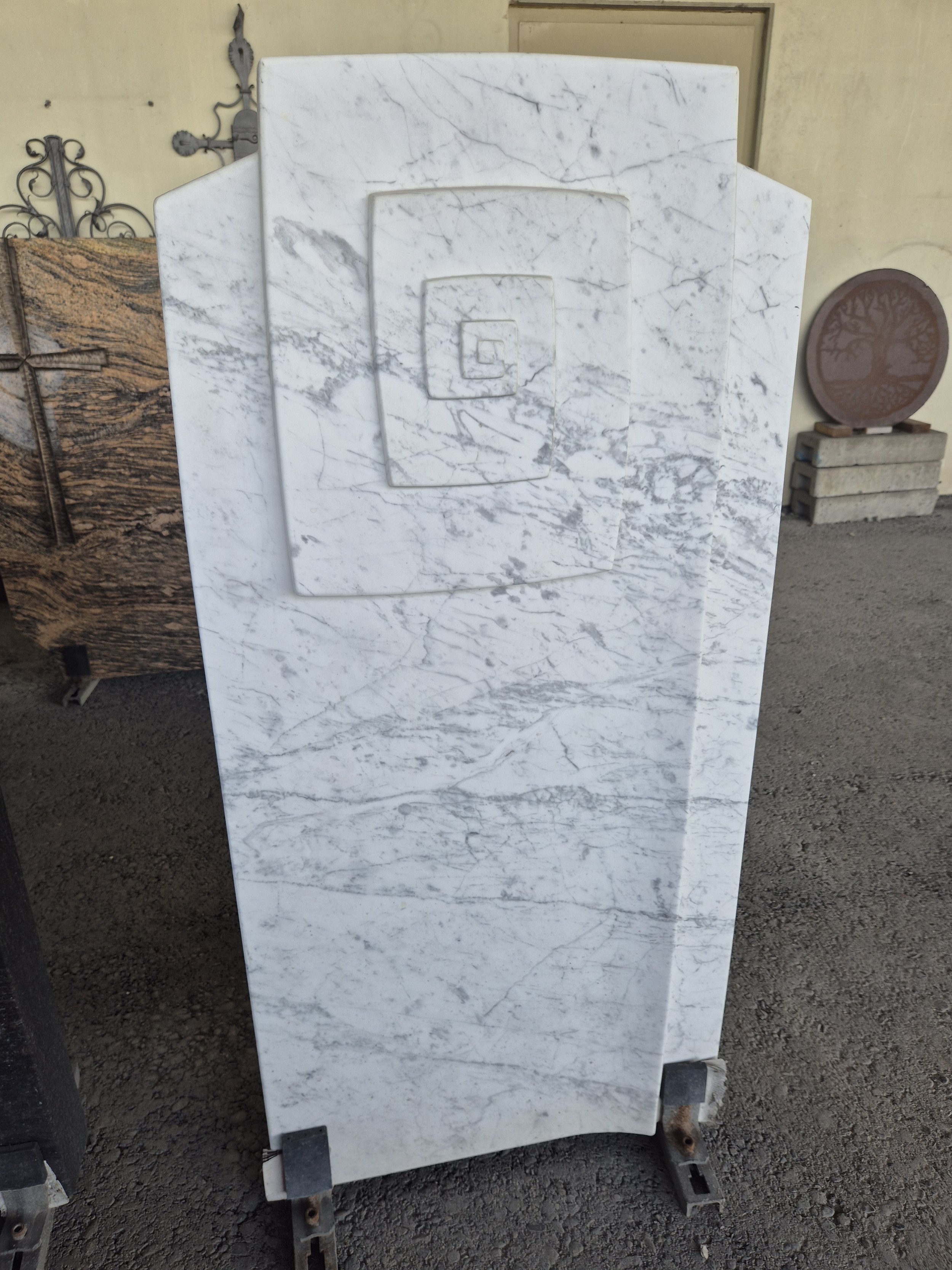 Schwarzer Marmor-Cross mit Metallrahmen und verziertem Holzbalken im Hintergrund.