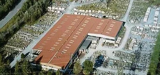 Luftaufnahme eines großen Gebäudes mit roten Dächern und umliegenden Park- und Parkplatzflächen.