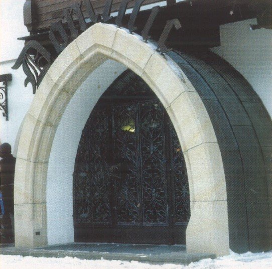 Ein gotisches Portal mit einer kleinen Person links daneben als Größenvergleich, inklusive Schnee davor.