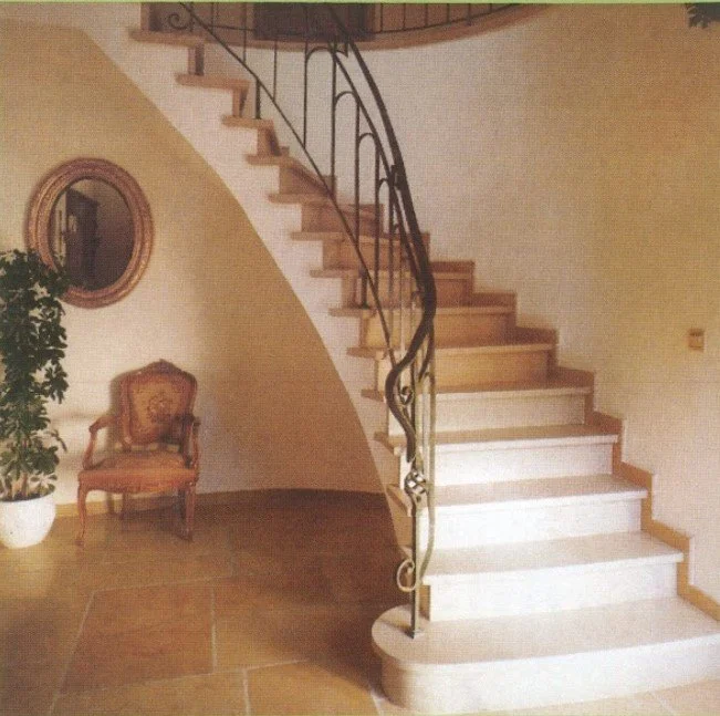 Innenaufnahme eines Hauses mit einer Holztreppe, einem Spiegel, einem Stuhl und einer Pflanze.