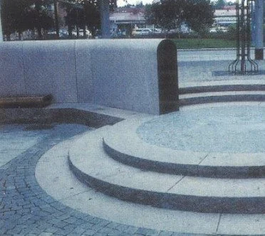 Drei halbkreisförmige Stufen und eine hohe schwarze Barriere vor einer Treppe im Außenbereich.
