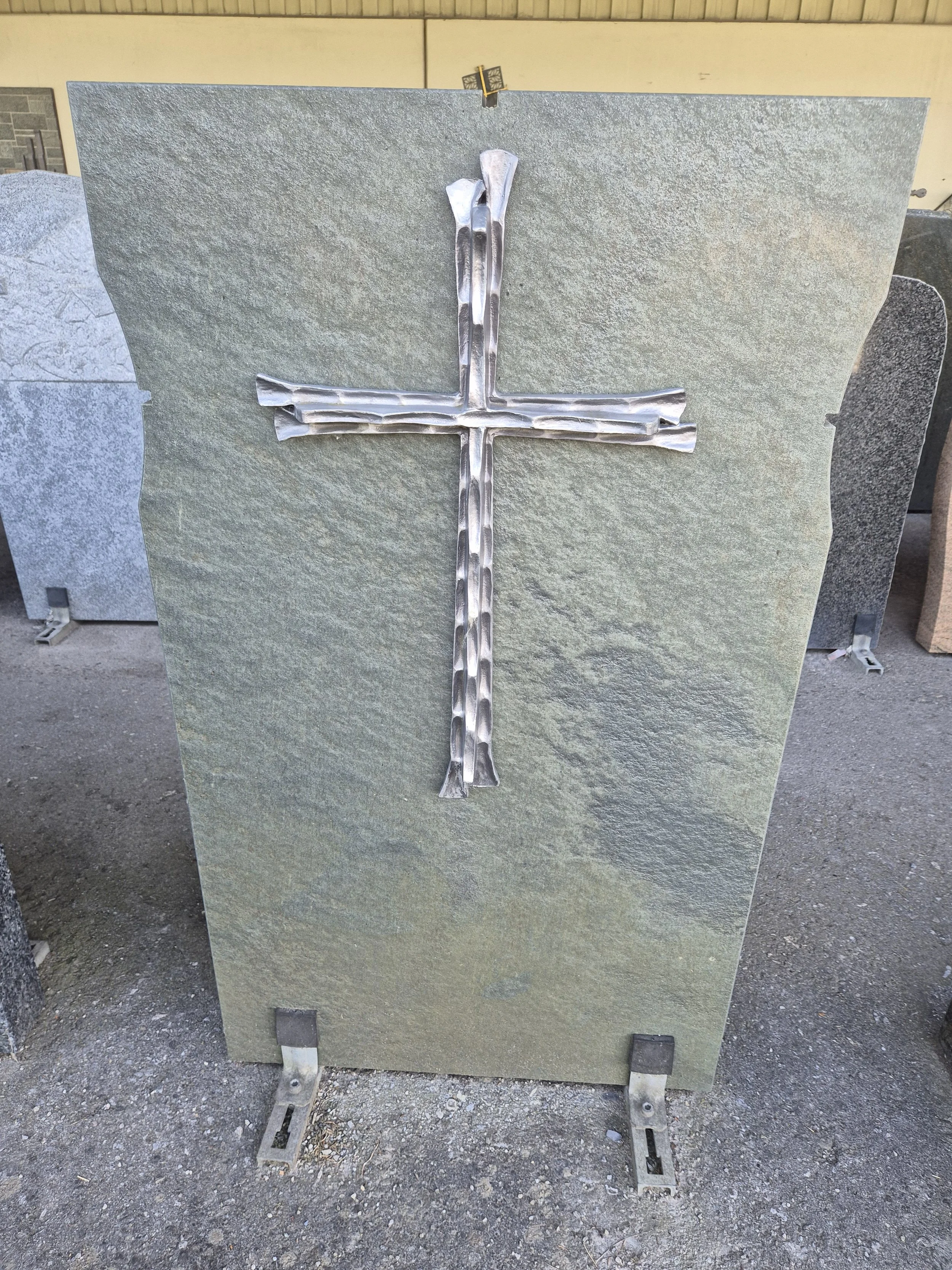 Granitplatte mit einem darauf montierten Metallkreuz.