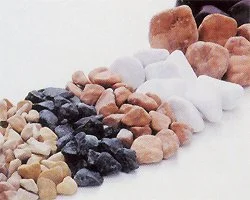 Mehrere Reihen von bunten, unbehandelten Steinen in verschiedenen Farben, auf weißem Hintergrund.