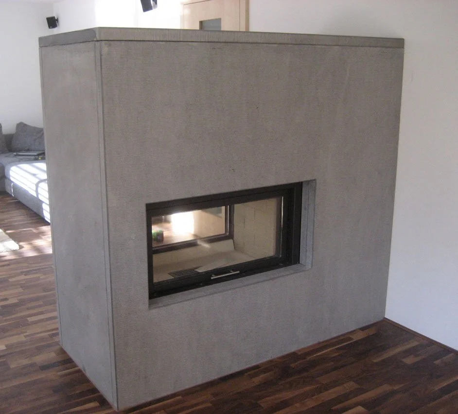 Moderner Kamin mit grauem Stoffbezug und schmalem Sichtfenster in einem Wohnzimmer mit Holzboden.