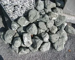 Steine auf einer schwarzen Oberfläche neben einem Plastikkorb