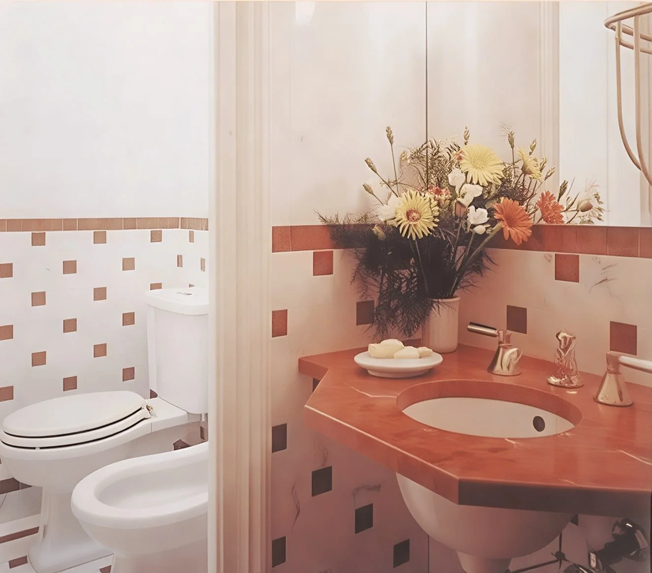 Badezimmer mit weißen Wänden, rotem Mosaikrand, Waschbecken mit Holzplatte, Blumenvasen mit Blumen, eine Toilette im Hintergrund.