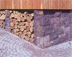 Stapel Holzbretter und Steine an einer Ecke neben einer gepflasterten Fläche.