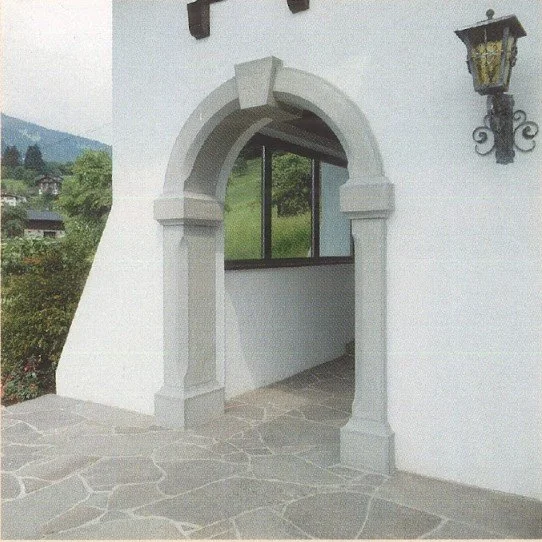 Archikonzession im weißen Wand mit Fenster im Hintergrund und laternenähnlicher Leuchte an der Wand, auf Steinboden.