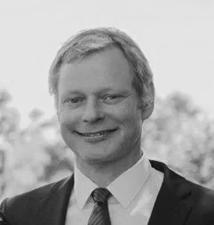 Porträt eines Mannes in formeller Kleidung, lächelnd, im Freien, schwarz-weiß