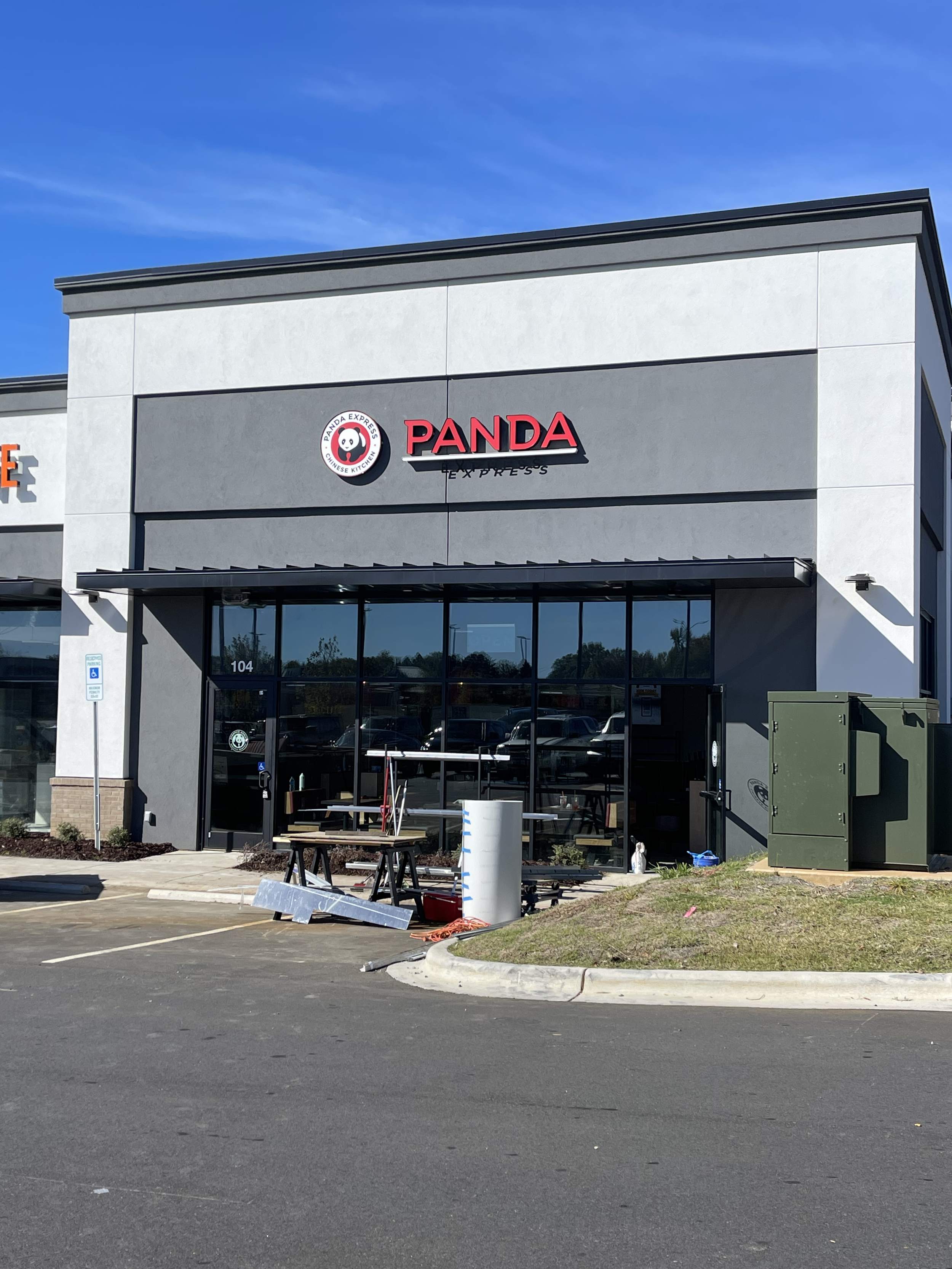 Front view of a Panda Express restaurant under construction, with tools and equipment outside, and the store's logo on the building. Wallpaper instalating in Charlotte and near