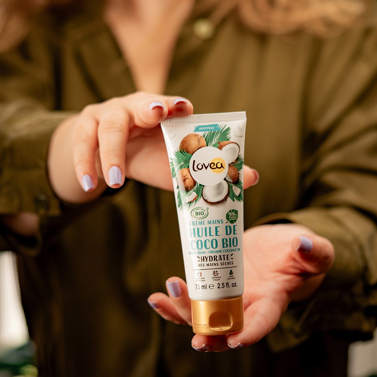 A person holding a tube of Lovea organic coconut oil hand cream.