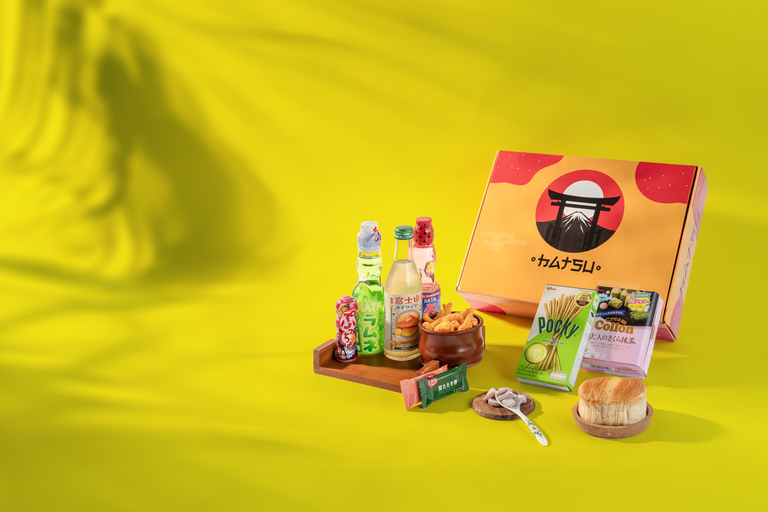 Japanese snacks and beverages arrangement with a gift box on a yellow background