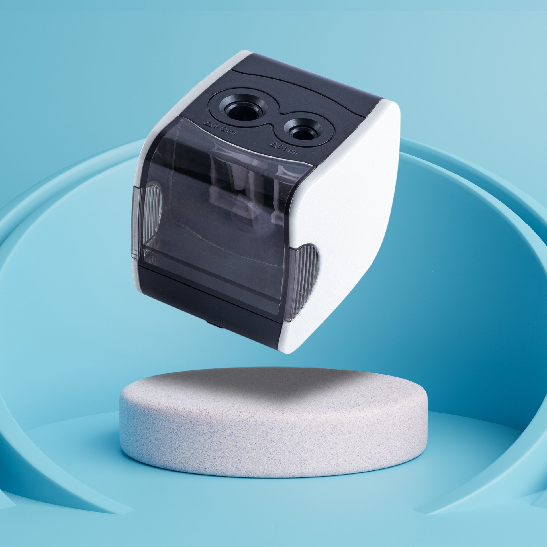 A modern automatic pencil sharpener with a black and white body, mounted on a blue surface, with a shavings container and two holes for inserting pencils.
