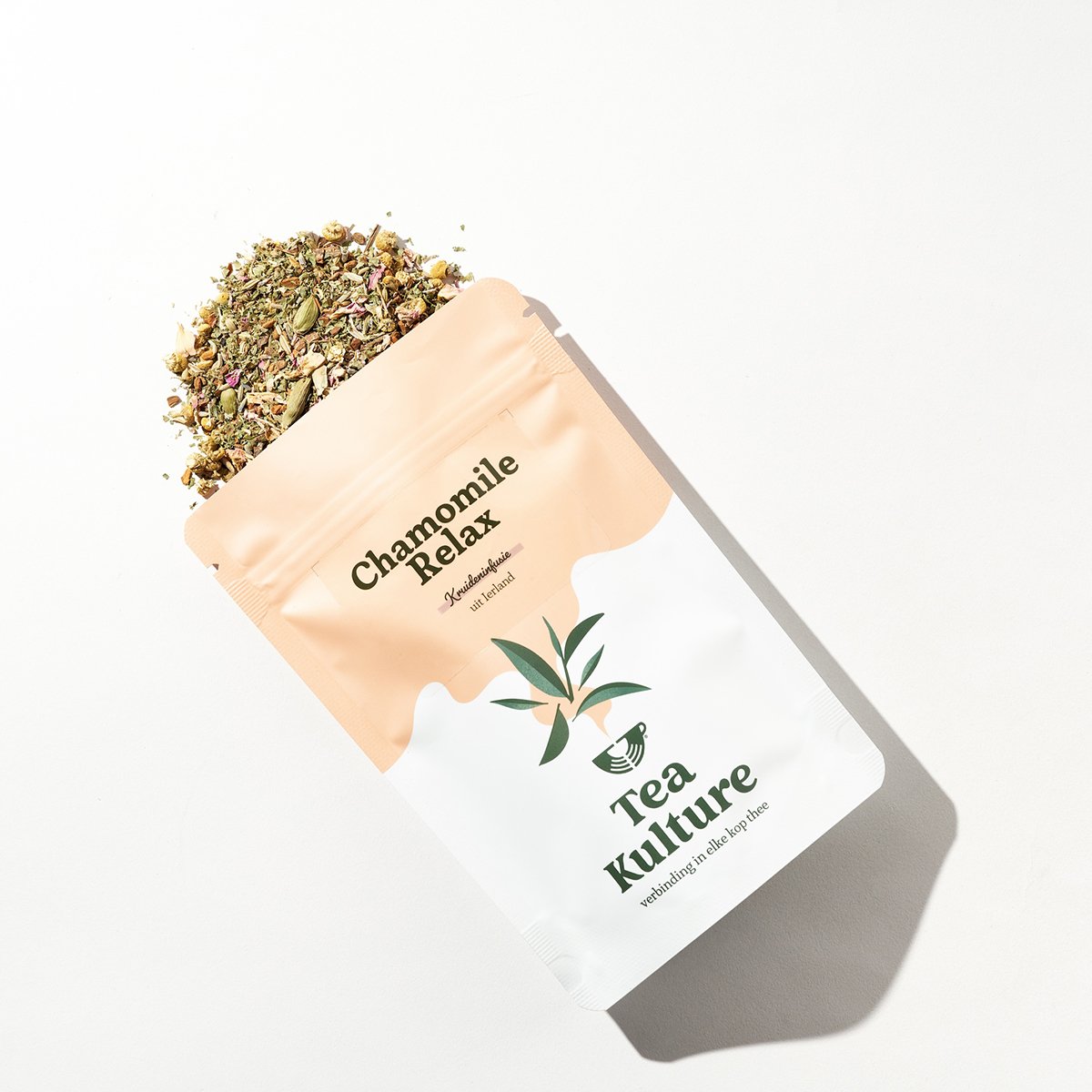 A package of Chamomile Relax herbal tea from Tea Kulture with loose chamomile and herbal mixture spilling out on a white background.