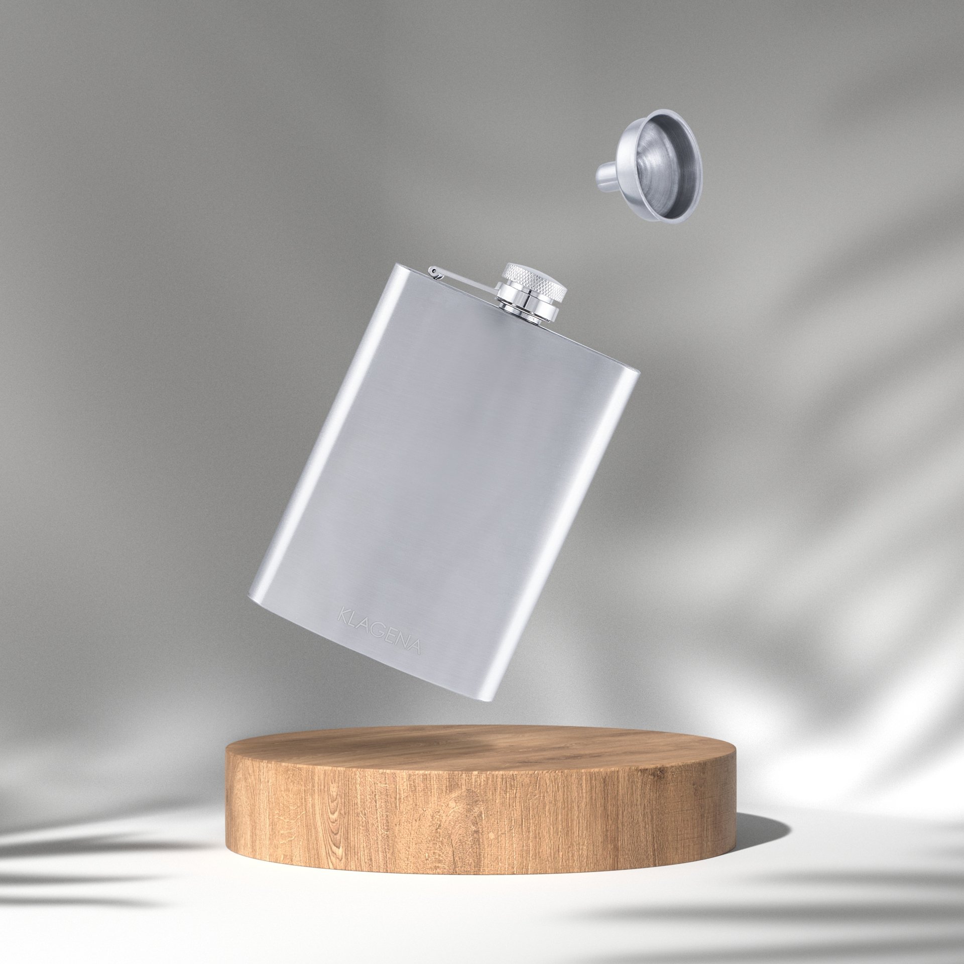 A silver metal flask with a screw-on lid, suspended mid-air above a wooden platform against a gray background.