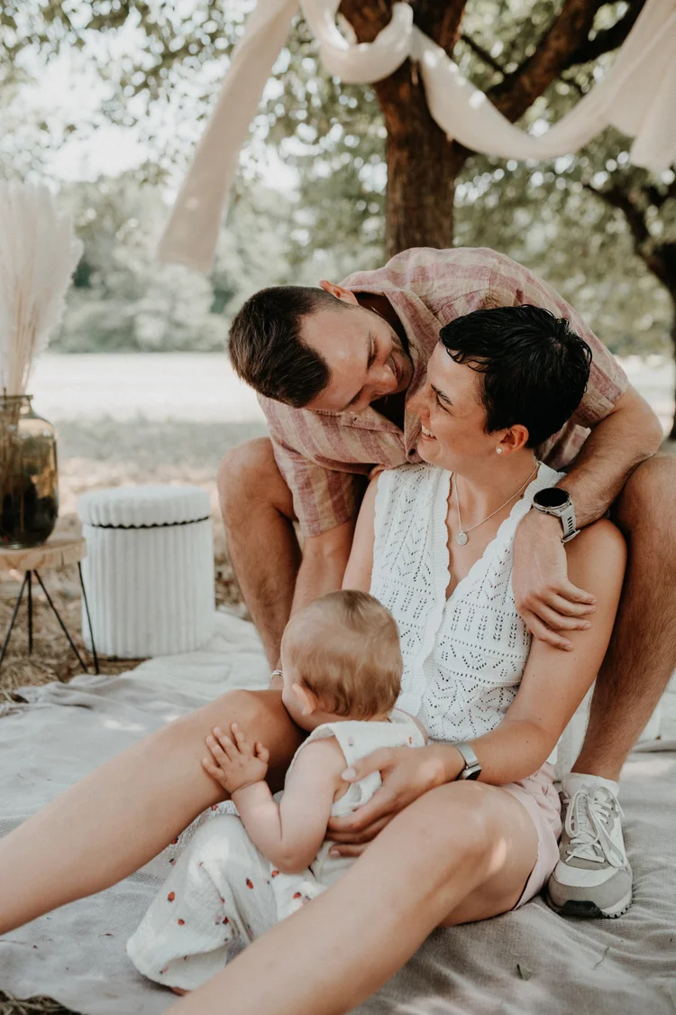 Eltern kuscheln mit ihrem Baby auf der Picknickdecke