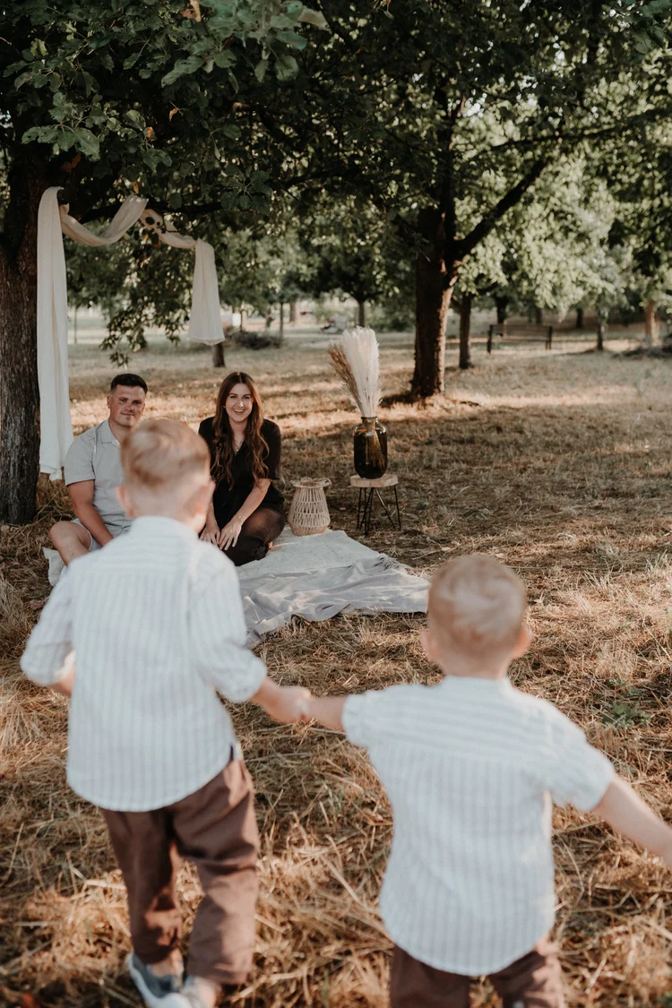 Kinder rennen ausgelassen zu ihren Eltern auf der Picknickdecke