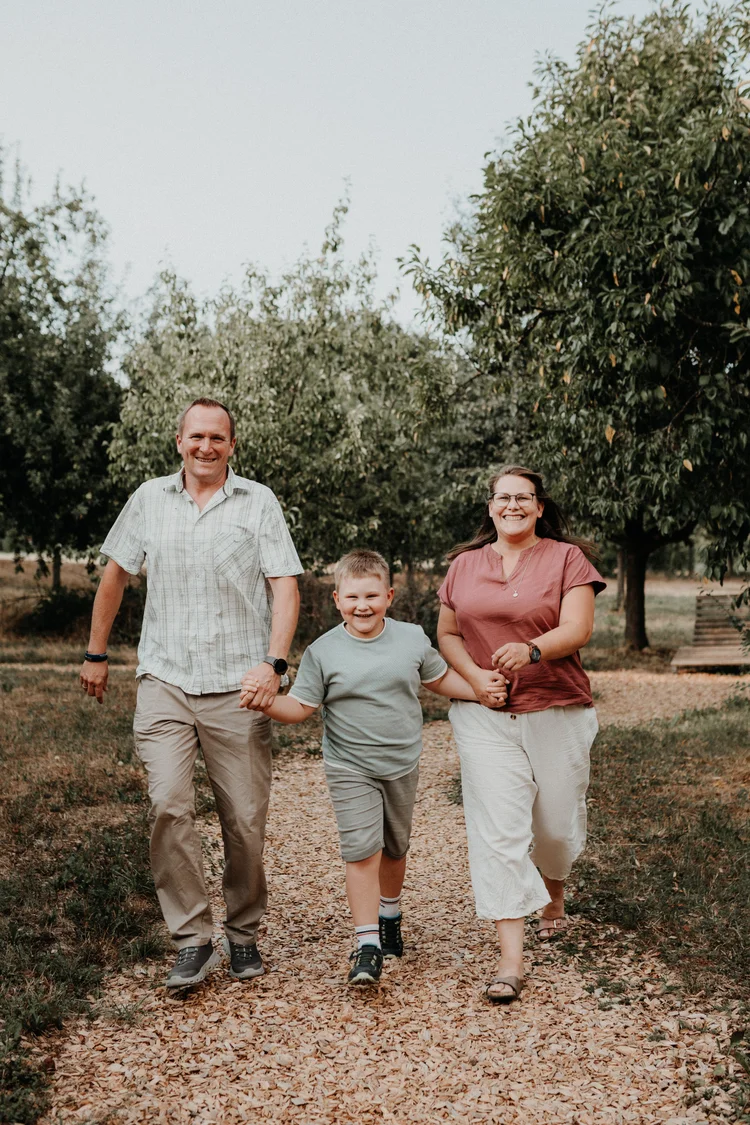 Familie läuft Hand in Hand den Feldweg entlang