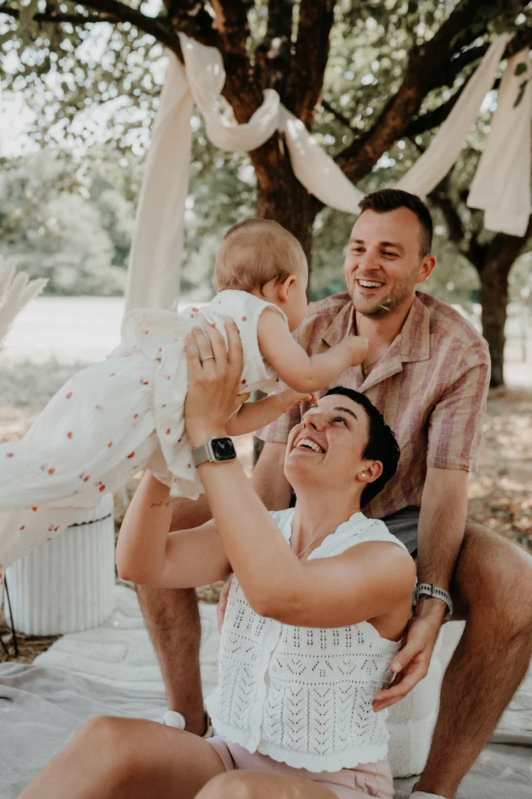 Vater hebt das Baby in die Luft, Mutter lacht dazu