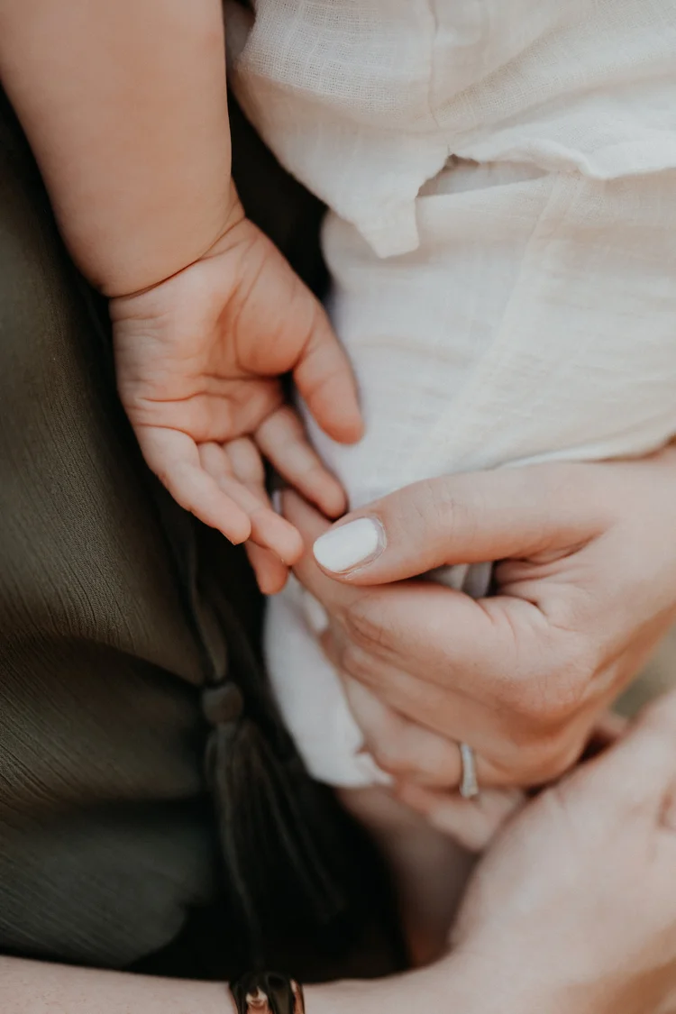 Babyhand liegt geborgen in den Händen der Eltern