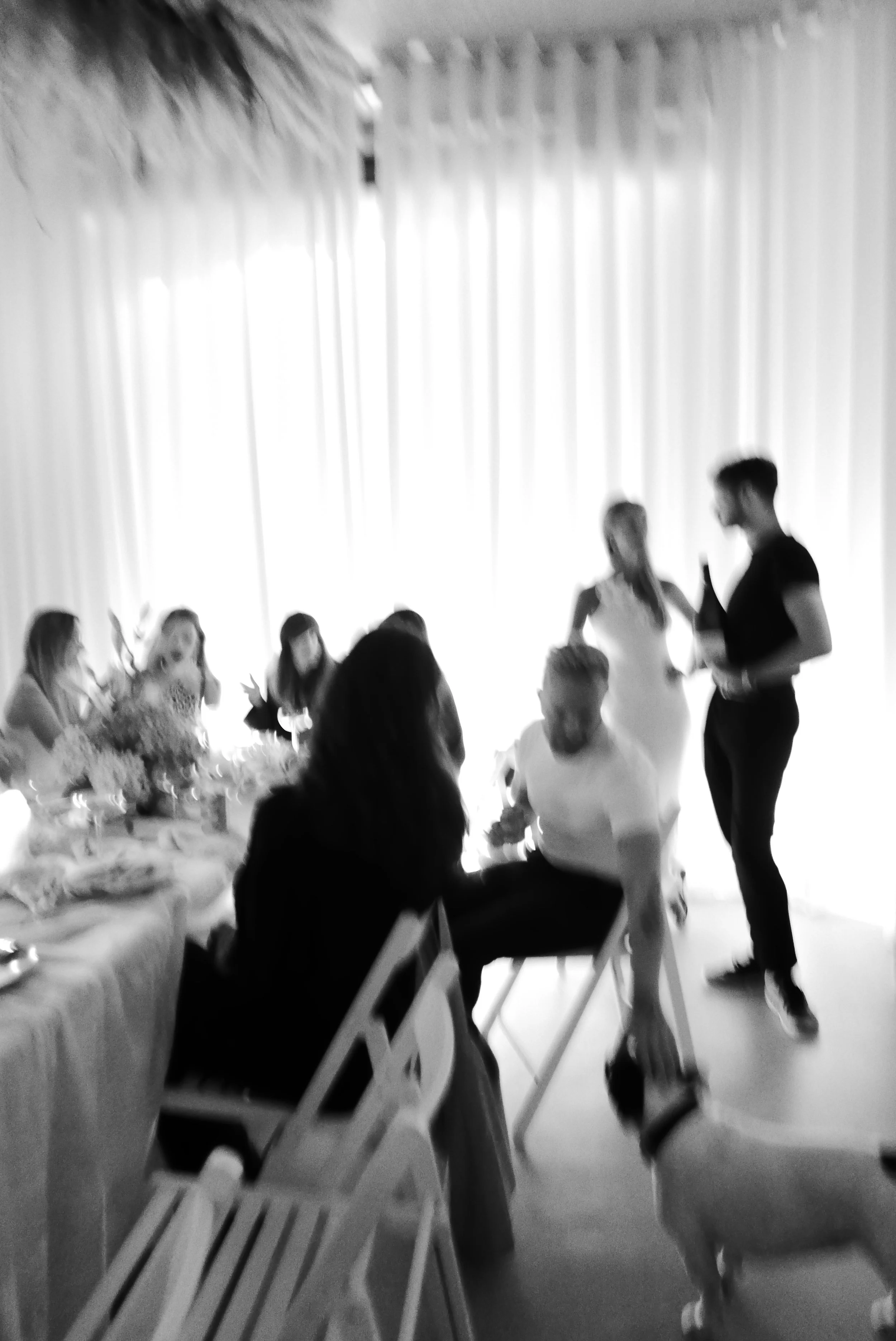 People gathered at a table during a celebration, with two individuals standing and talking.