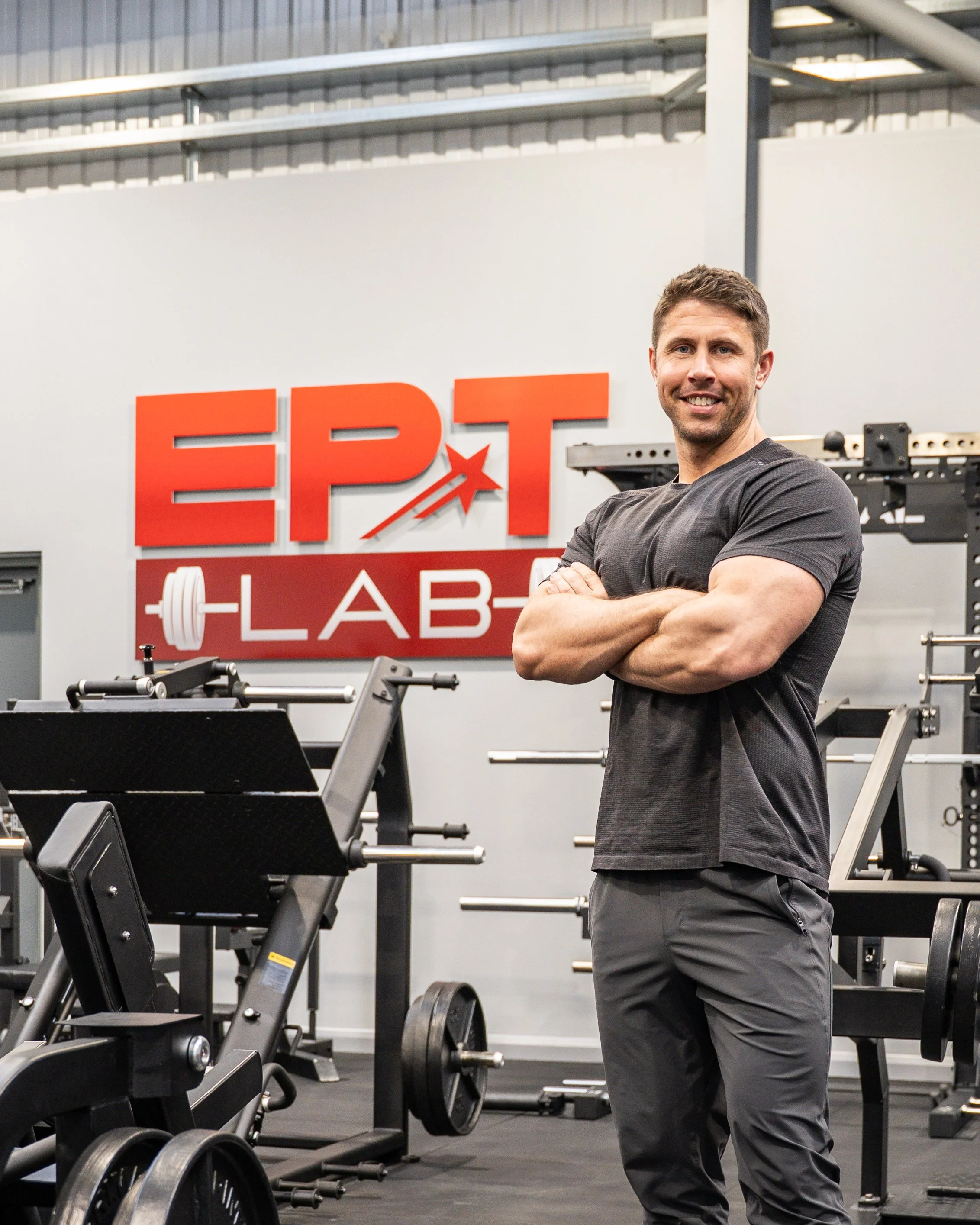 Gareth Sapstead standing in the EPT Lab gym with arms crossed, smiling in front of a red and white "EPT LAB" sign, surrounded by workout equipment.