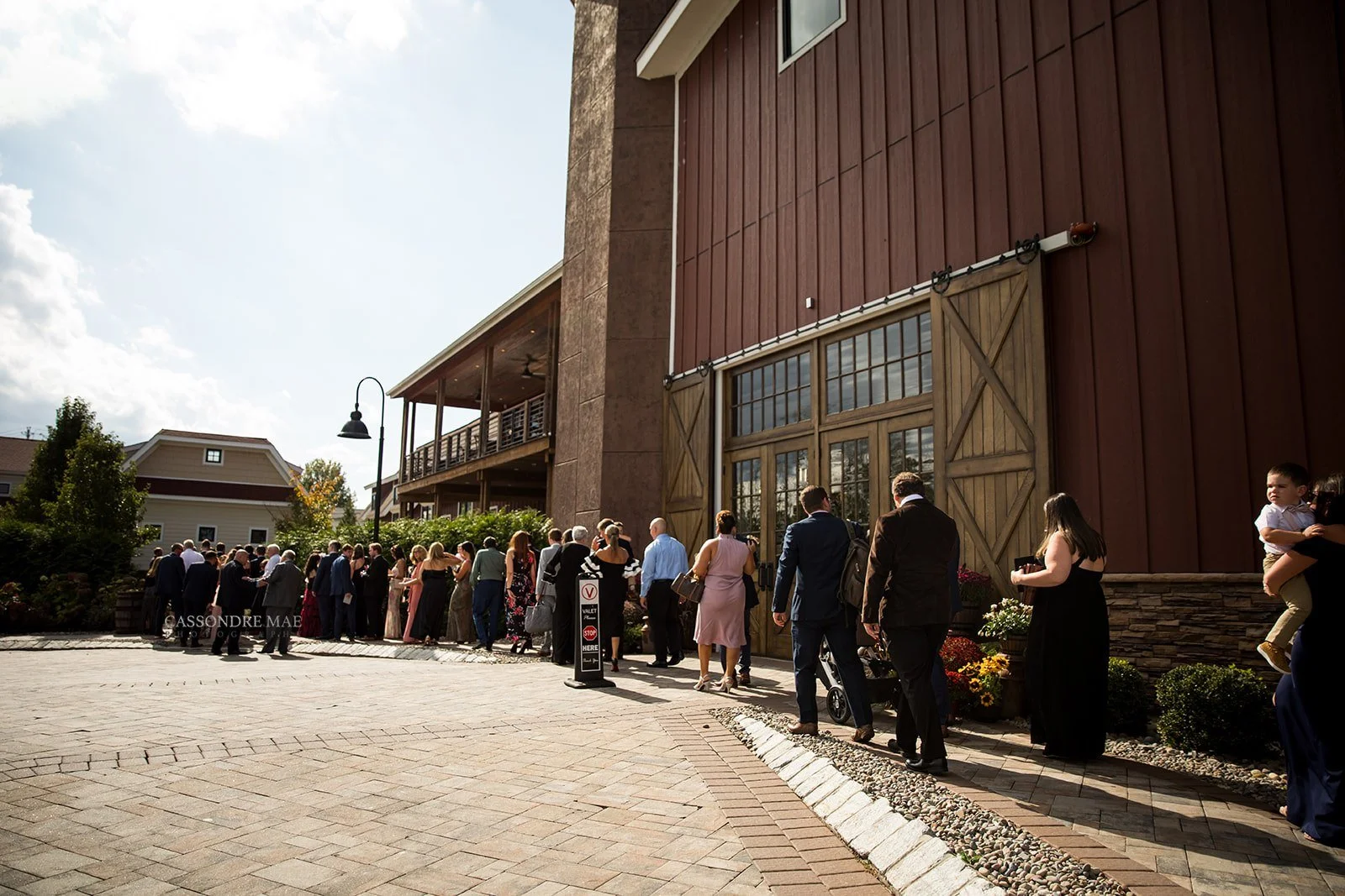 Wedding guests walking into the grand sliding wooden doors of the modern red barn exterior at The Barn at Villa Venezia
