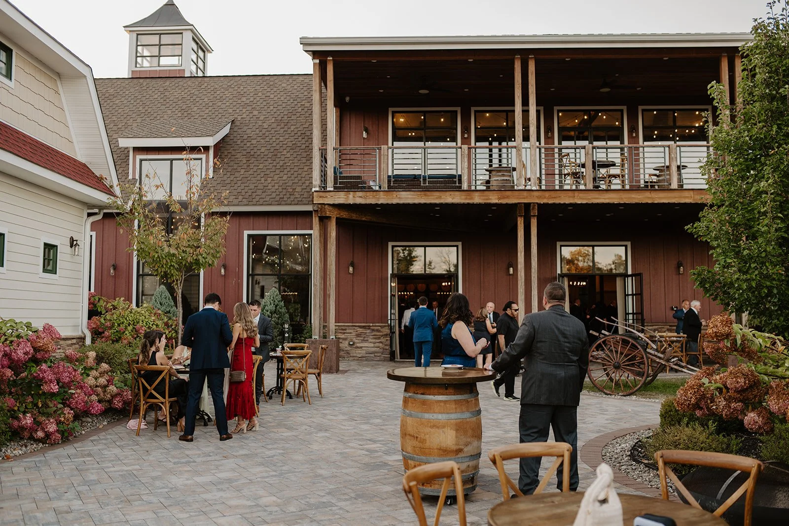 Wedding guests leisurely chat outside The Barn wedding venue in Hudson Valley