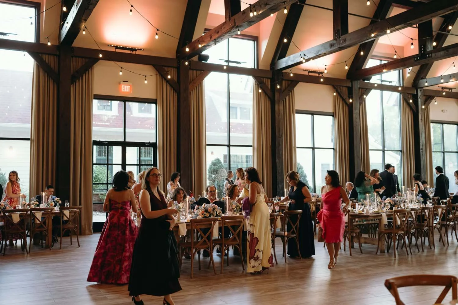 Guests mingling inside the high ceiling reception space at The Barn at Villa Venezia under warm bistro lights