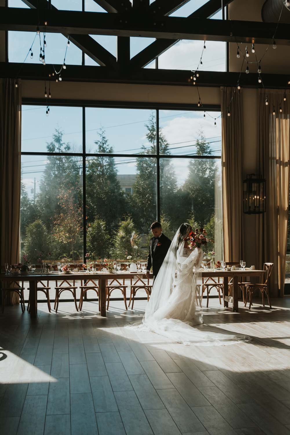 Bride and groom standing in from of floor to ceiling windows at a Hudson Valley barn wedding venue