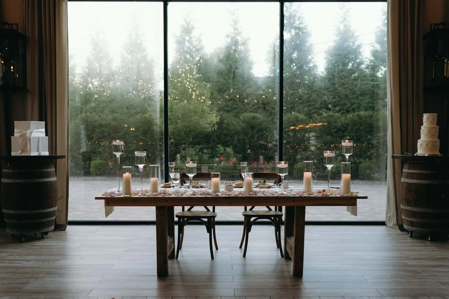 Romantic candlelit sweetheart table at The Barn at Villa Venezia set against floor to ceiling outdoor windows