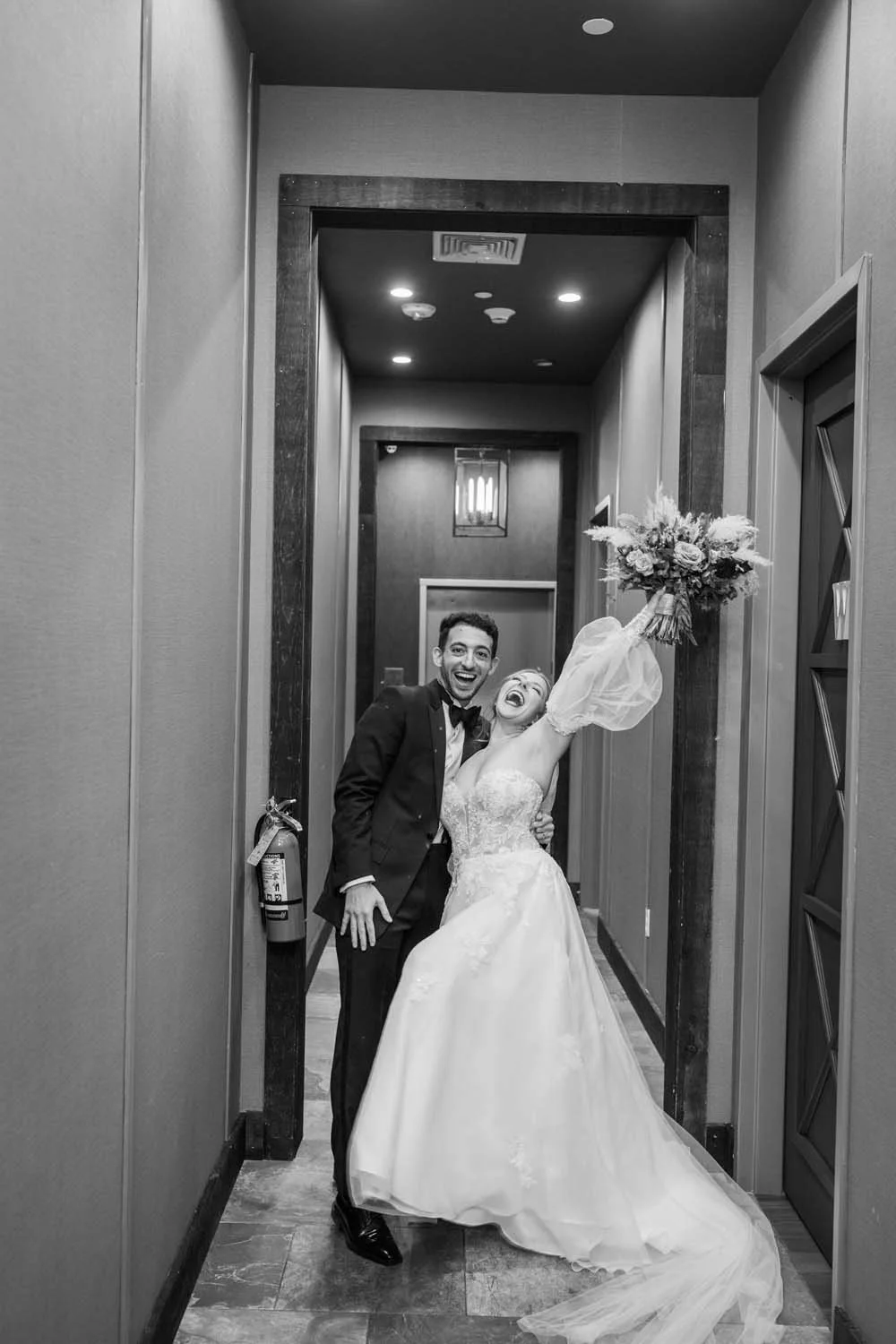 A black and white photo of a bride and groom celebrating after their ceremony