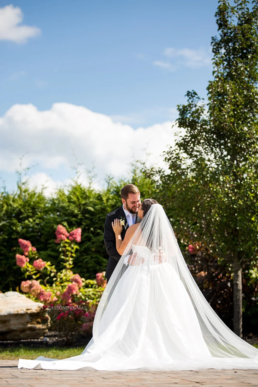 Bride and groom embracing during their outdoor portrait session with lush summer greenery in upstate NY