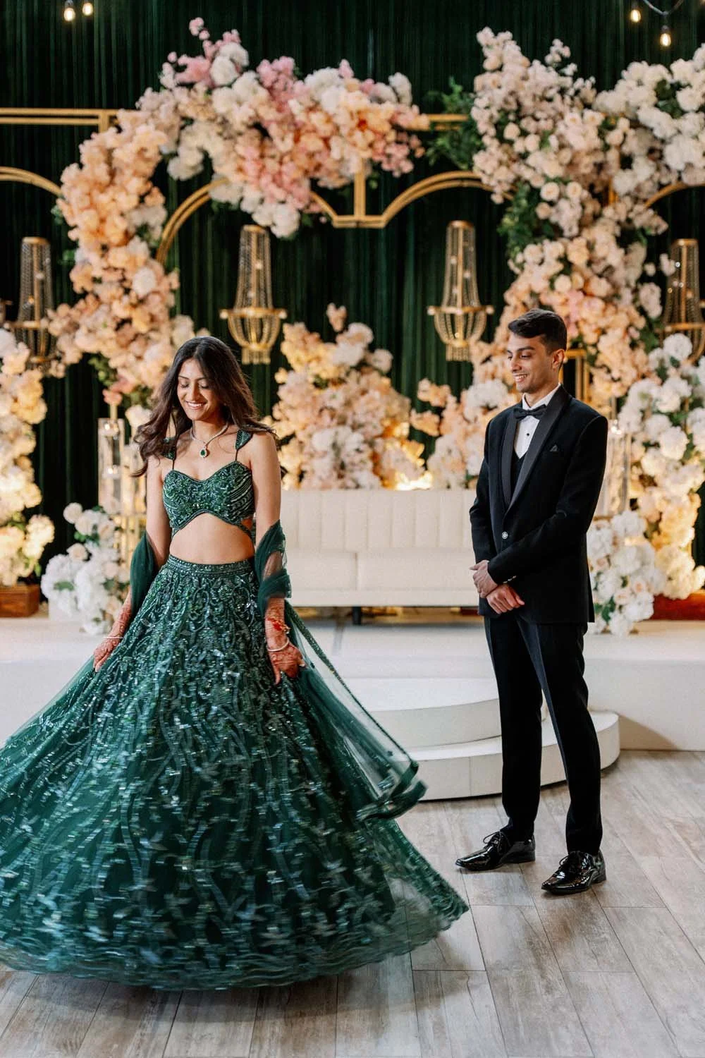 A couple is photographed in their reception hall with jewel tones and lush, peachy florals.