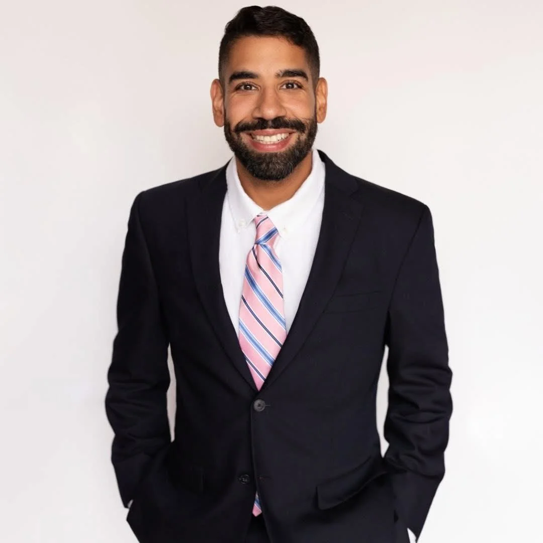 Alberto Deleon, Licensed Master Social Worker at Cornerstone Counseling, stands smiling, wearing hoop earrings, a patterned blouse, and a gold necklace.