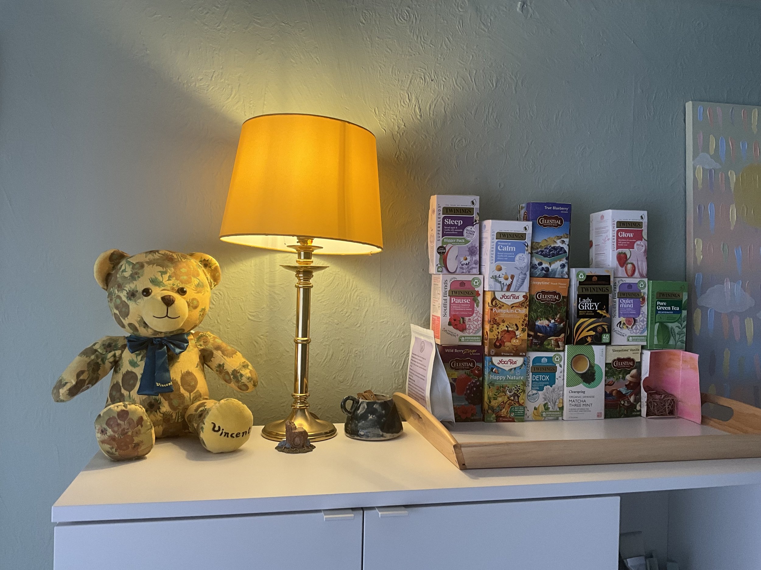 an image of a teddy bear, a yellow lamp shining warm light, and a selection of teas.