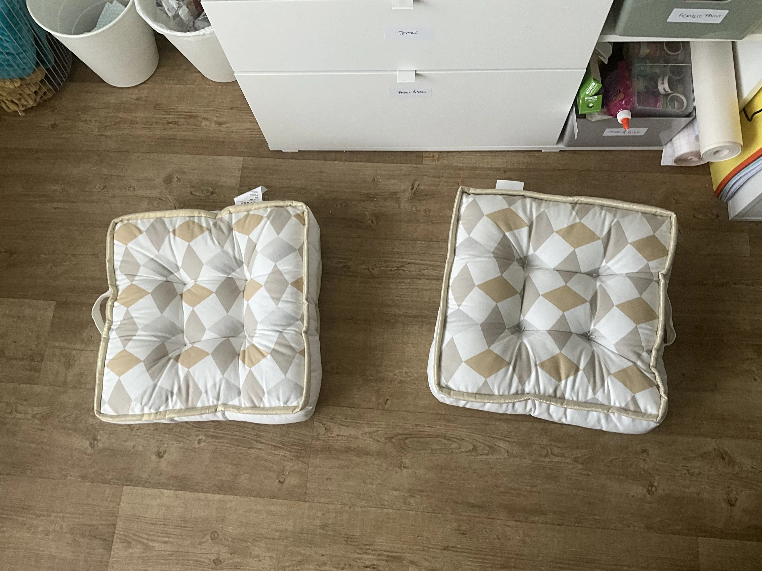 an image of two square thick floor cushions on the floor in the therapy studio in front of the materials cupboard.
