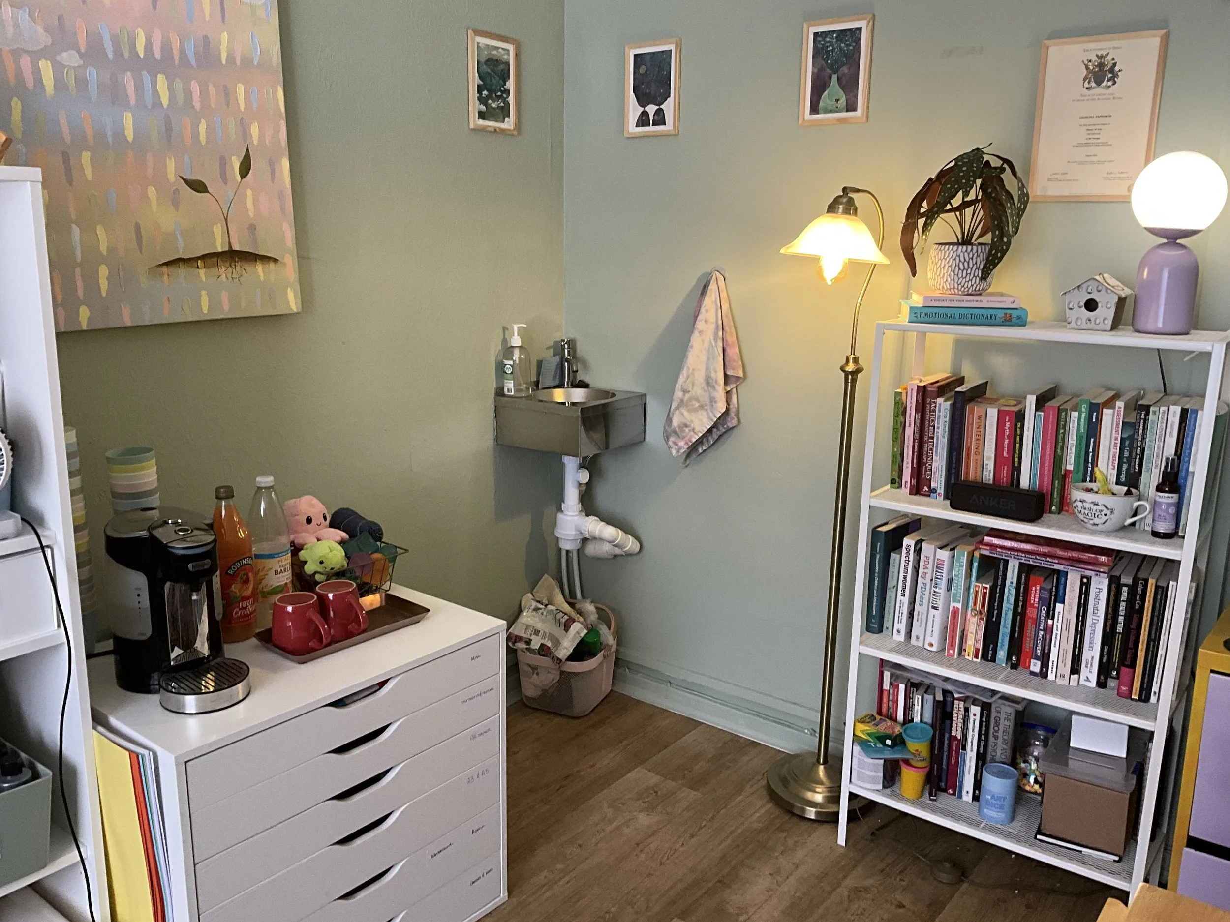 showing the distance between the paper storage, and the lamp and bookshelf with a small sink in the back corner.