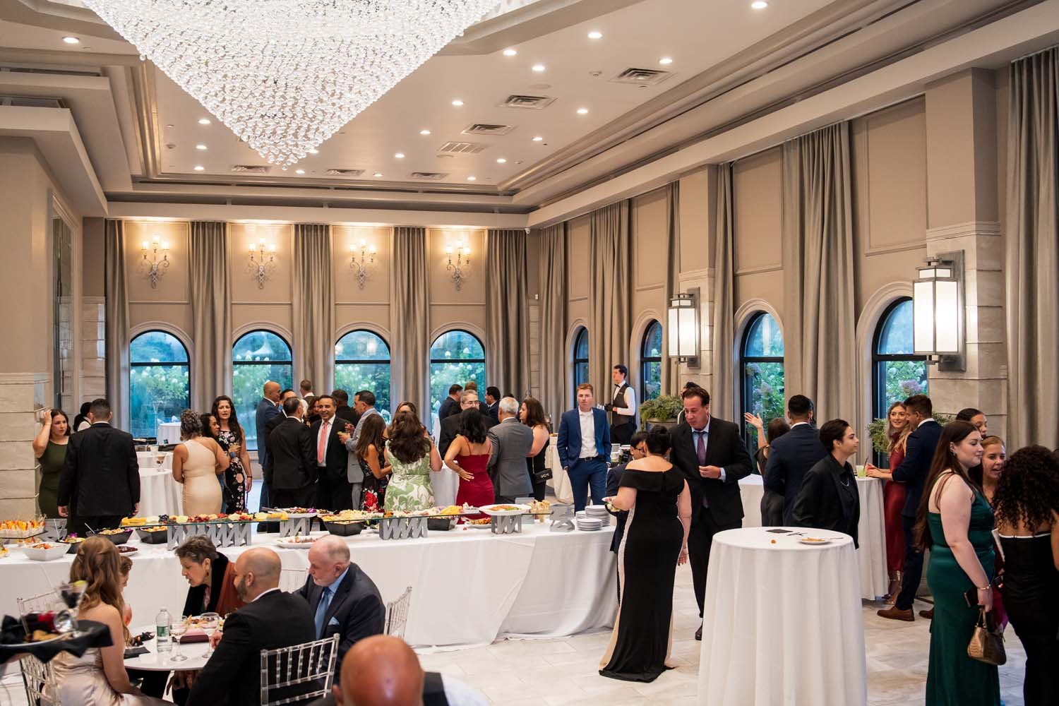 Wide indoor shot of wedding guests socializing inside the elegant, high-ceilinged grand ballroom at Villa Venezia.