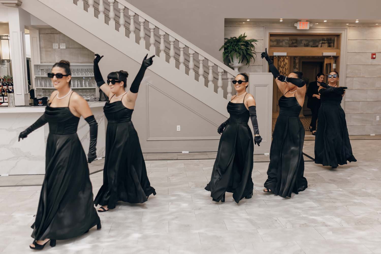Bridesmaids at a black tie New York wedding dance their way into a ballroom.
