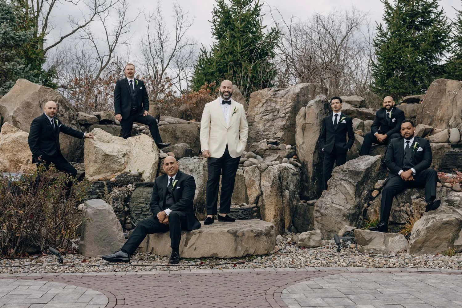 A groom and his groomsmen pose outside at their Hudson Valley wedding venue, dynamically posing.