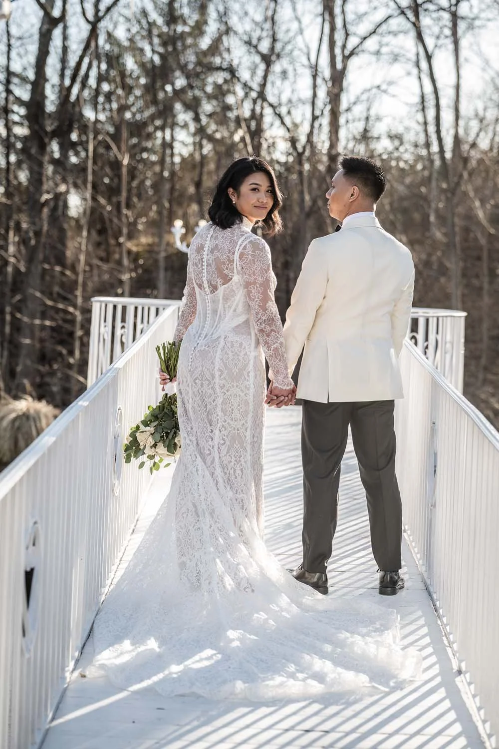 A bride and groom stand on a white railing bridge at Villa Venezia in Hudson Valley for a fairy tale, vintage-esque portrait.