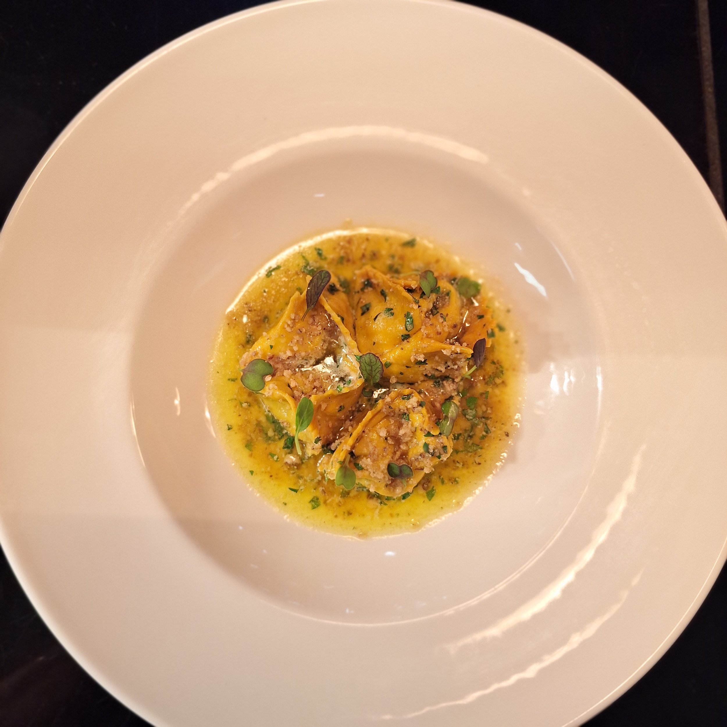 Plate of ravioli pasta topped with herbs and a light sauce.