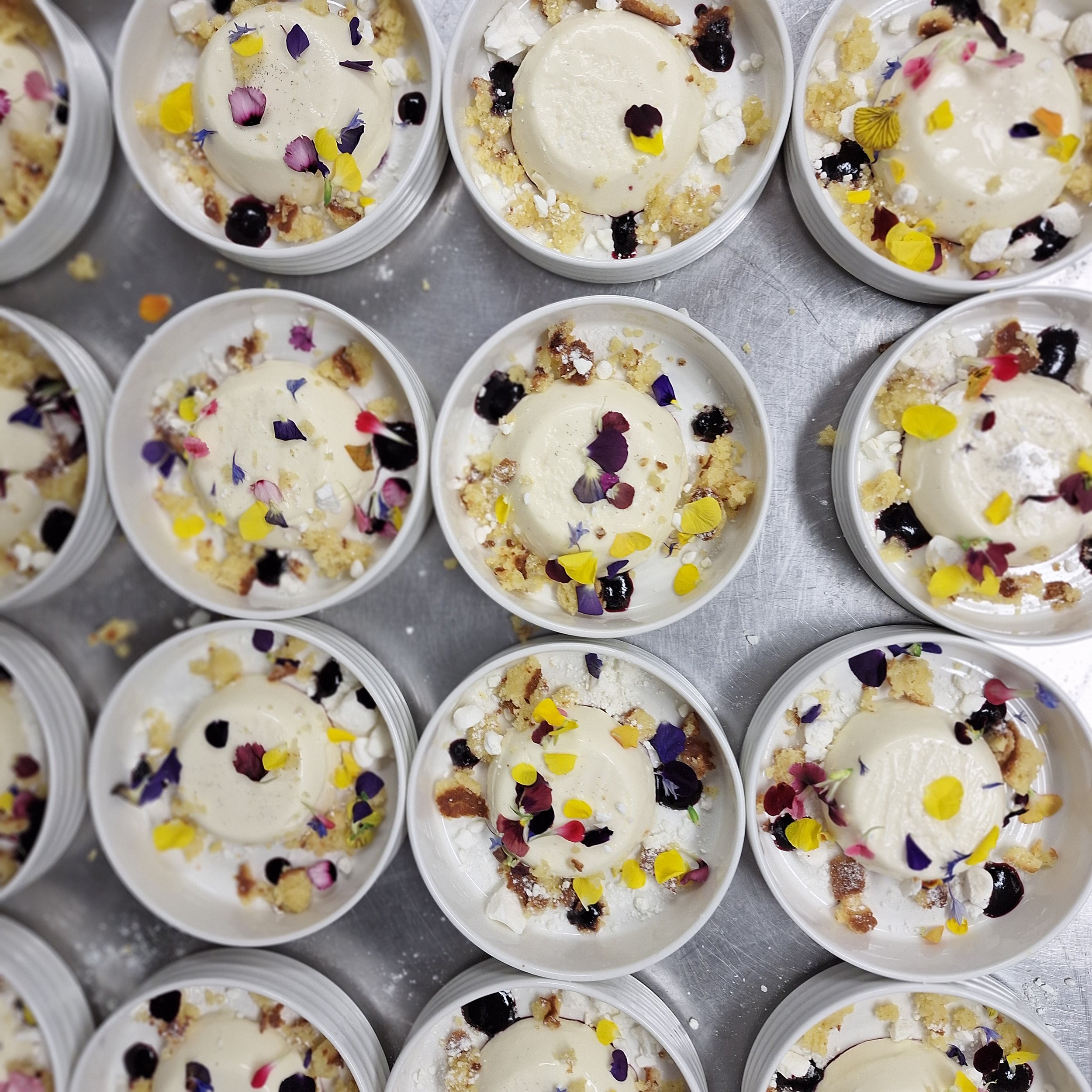 Multiple servings of dessert topped with edible flower petals and crumbles.