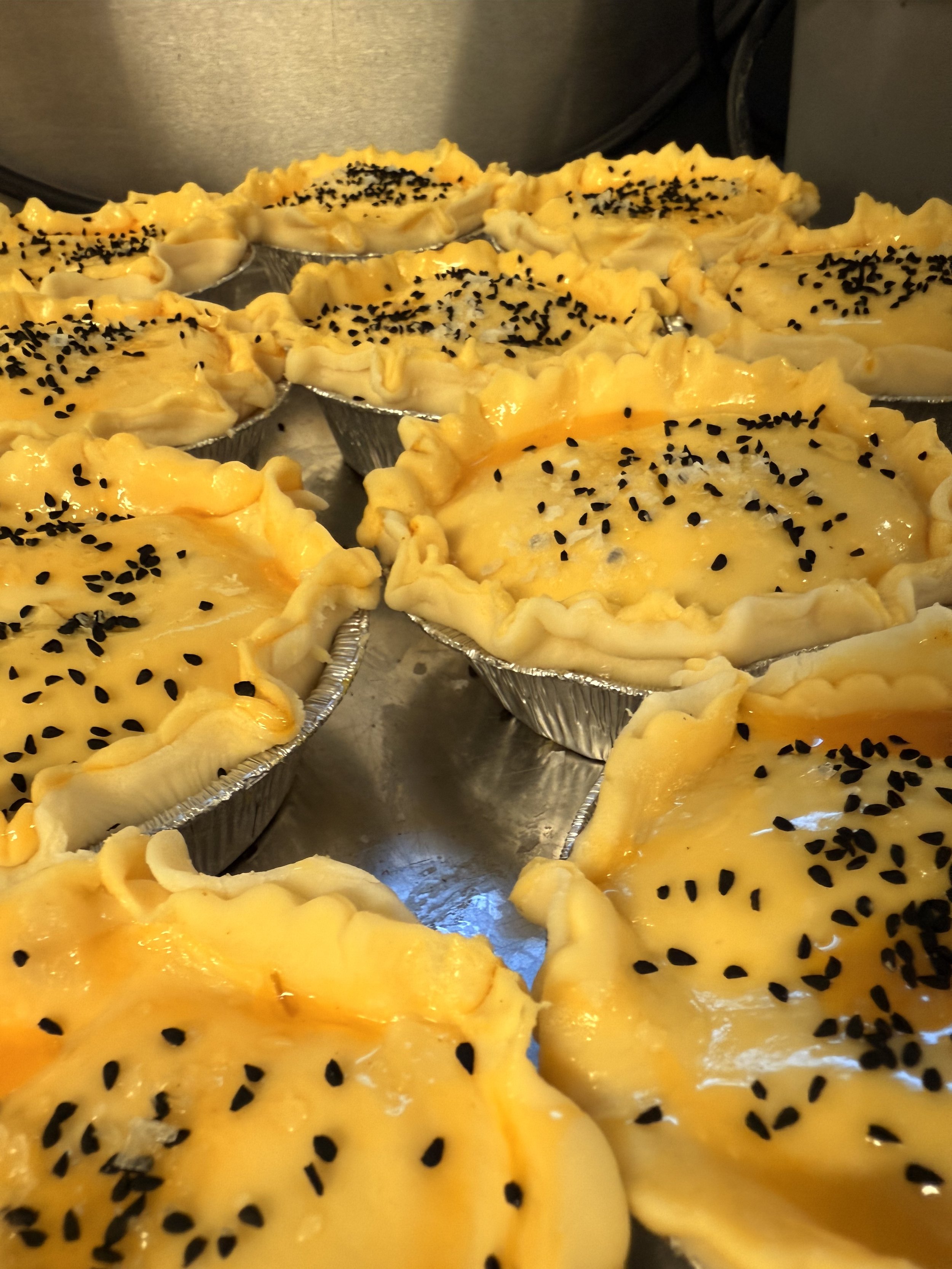 Small tart shells filled with egg, cheese, and black sesame seeds.